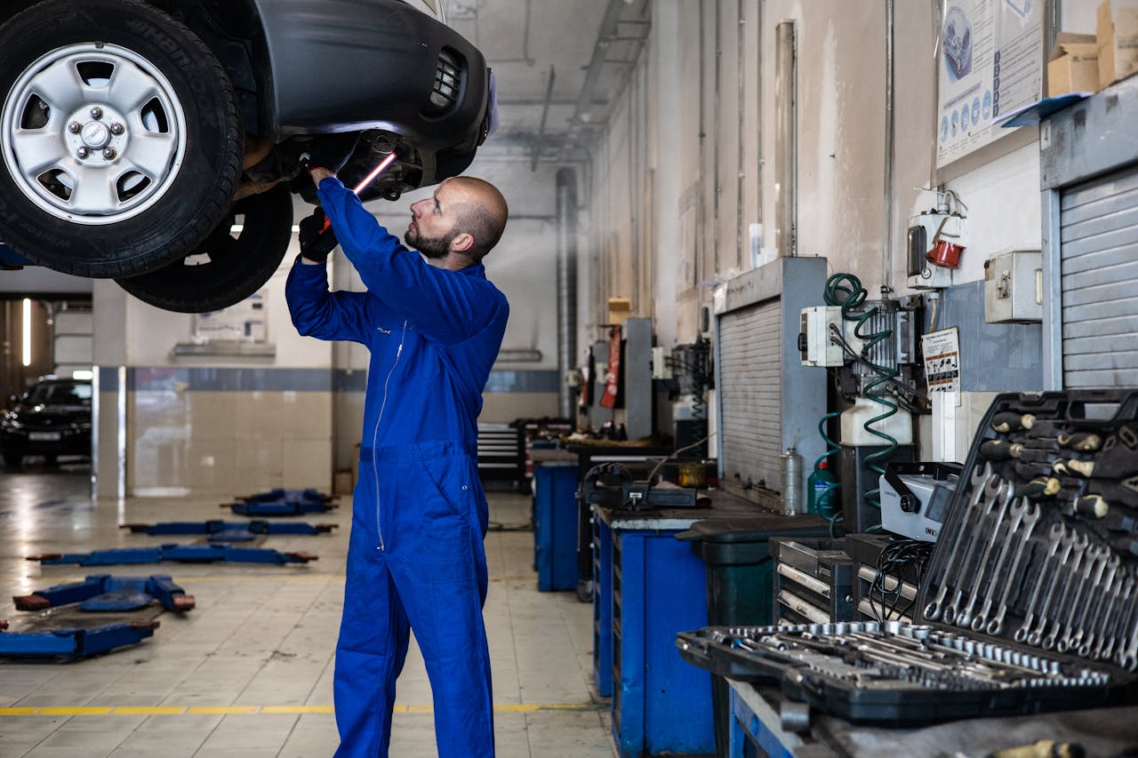 about-01 Mechanic inspecting a raised car in an auto workshop for maintenance and repair services.